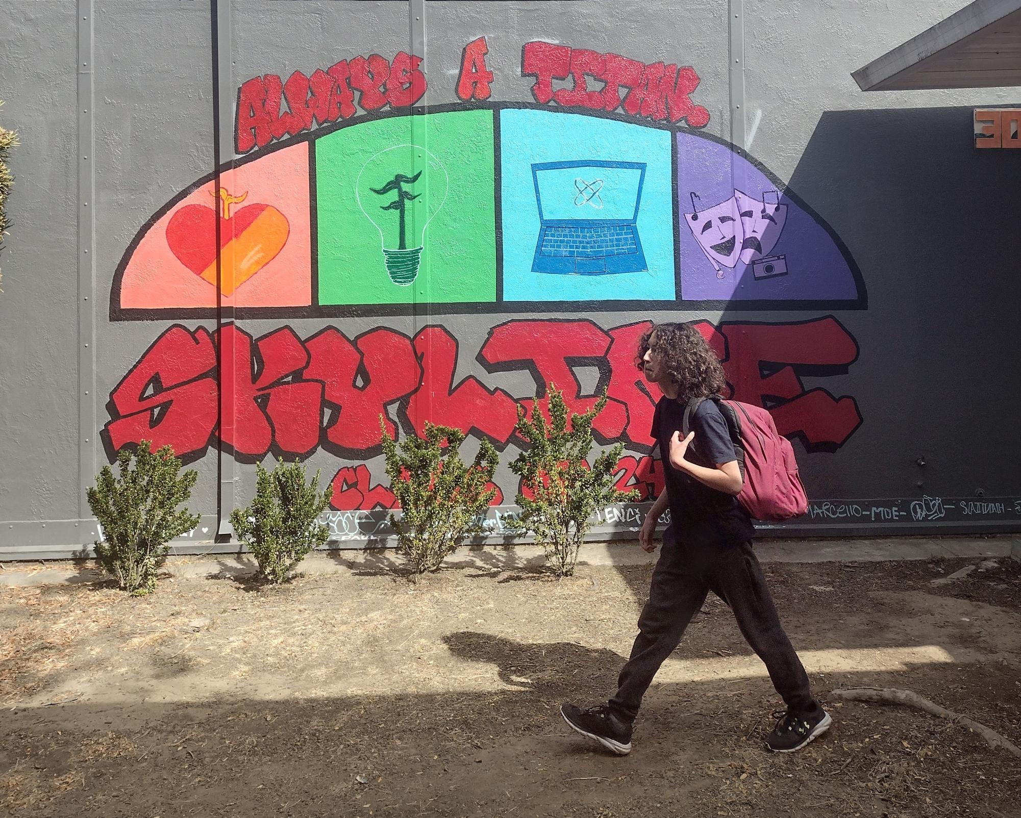 Freshman Cameron Ogden walks past a two-year-old mural that is already outdated. That's because two of the pathways on the mural are now closed. Students in Computer and VAPA pathways were placed in Arts Entertainment & Design pathway in August. Community Health &
Education and Green Energy pathways remain open.